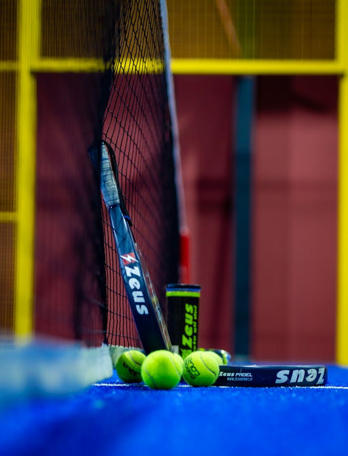 Colorful padel court with racket and balls highlights the sport's dynamic nature and vibrant setting.